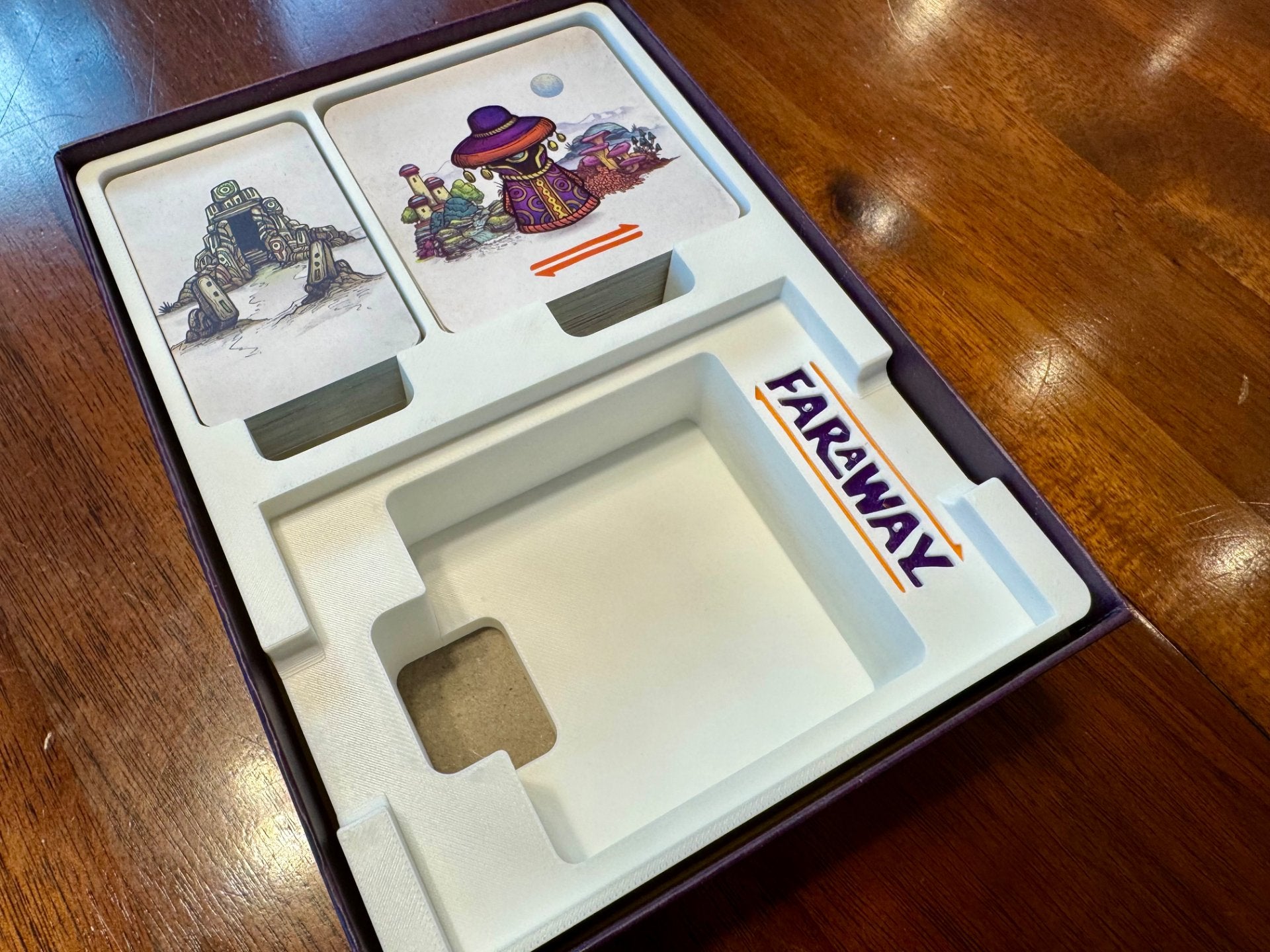 KreativLayers Faraway Game Insert, a board game organizer with compartments for cards and tokens, displayed on a table.