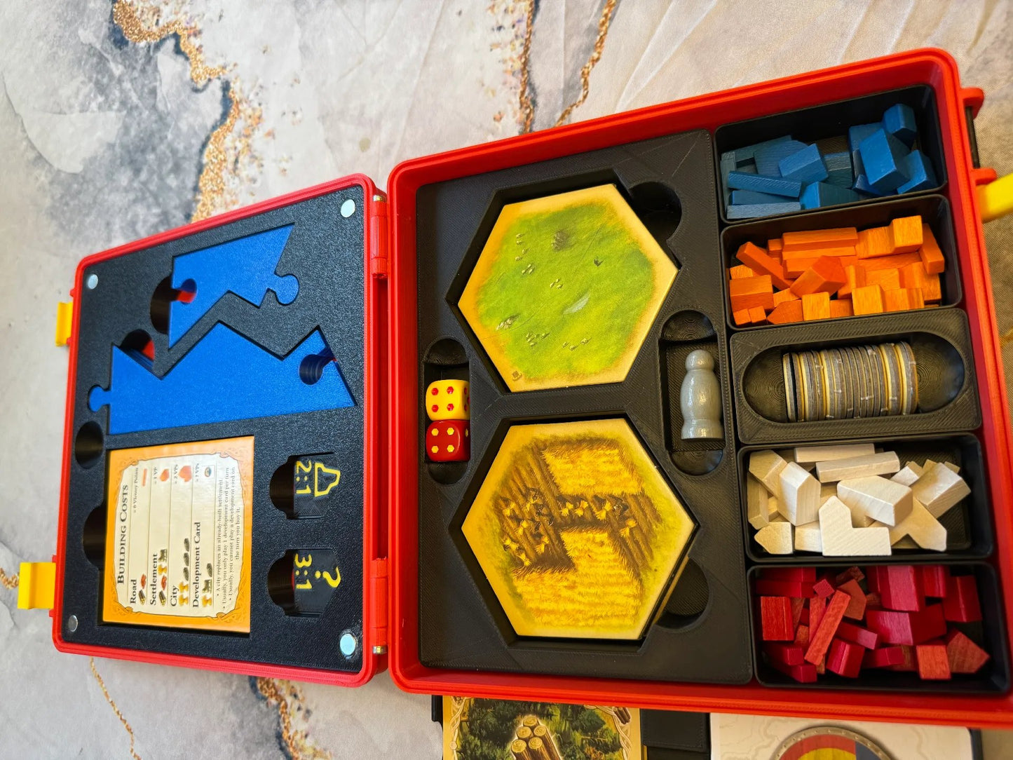 KreativLayers Catan Base Board Game Organizer with compartments for game pieces and cards, USA version box on a table.