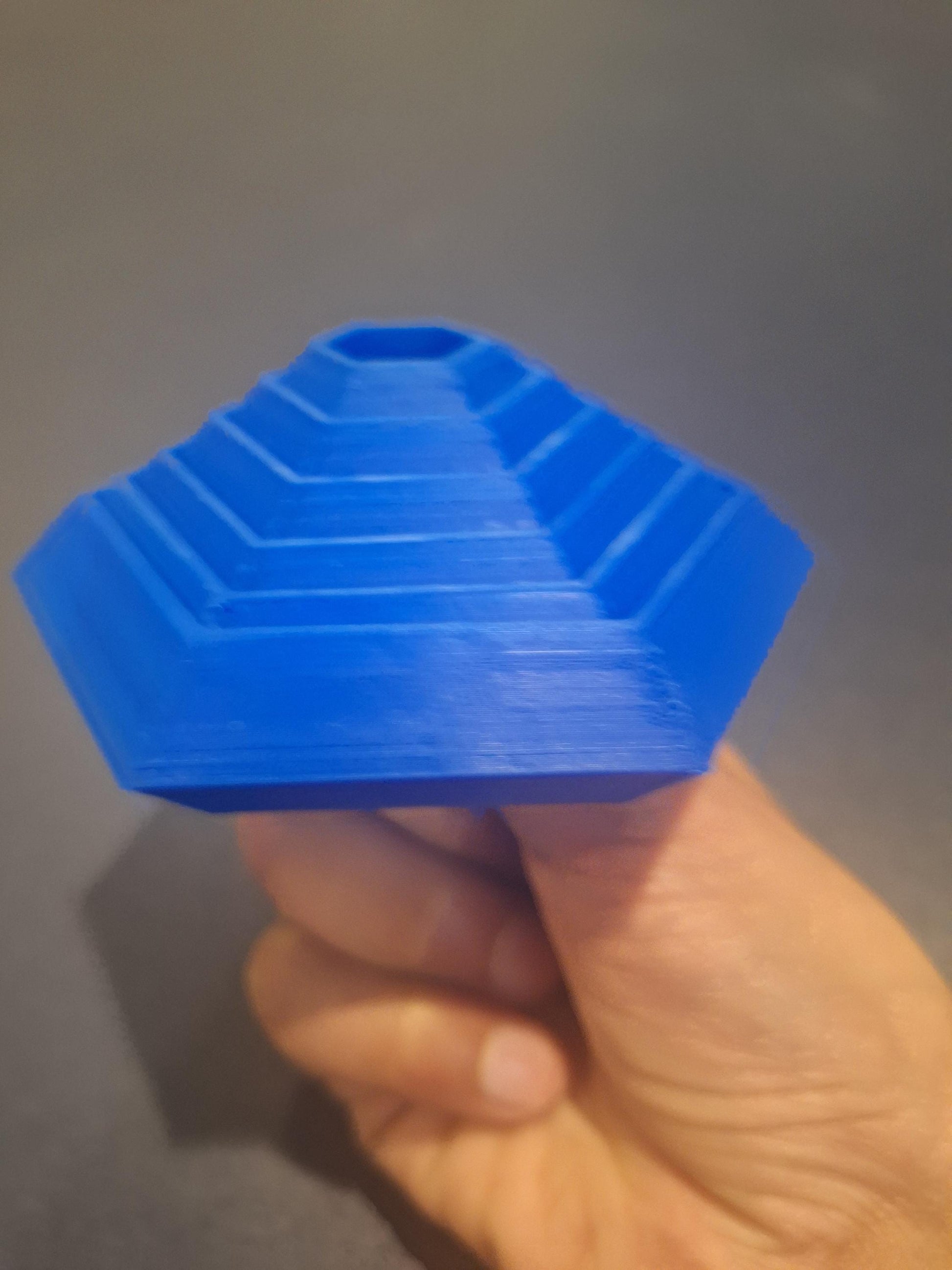 Hand holding a blue 3D printed board game organizer insert with stepped hexagonal layers