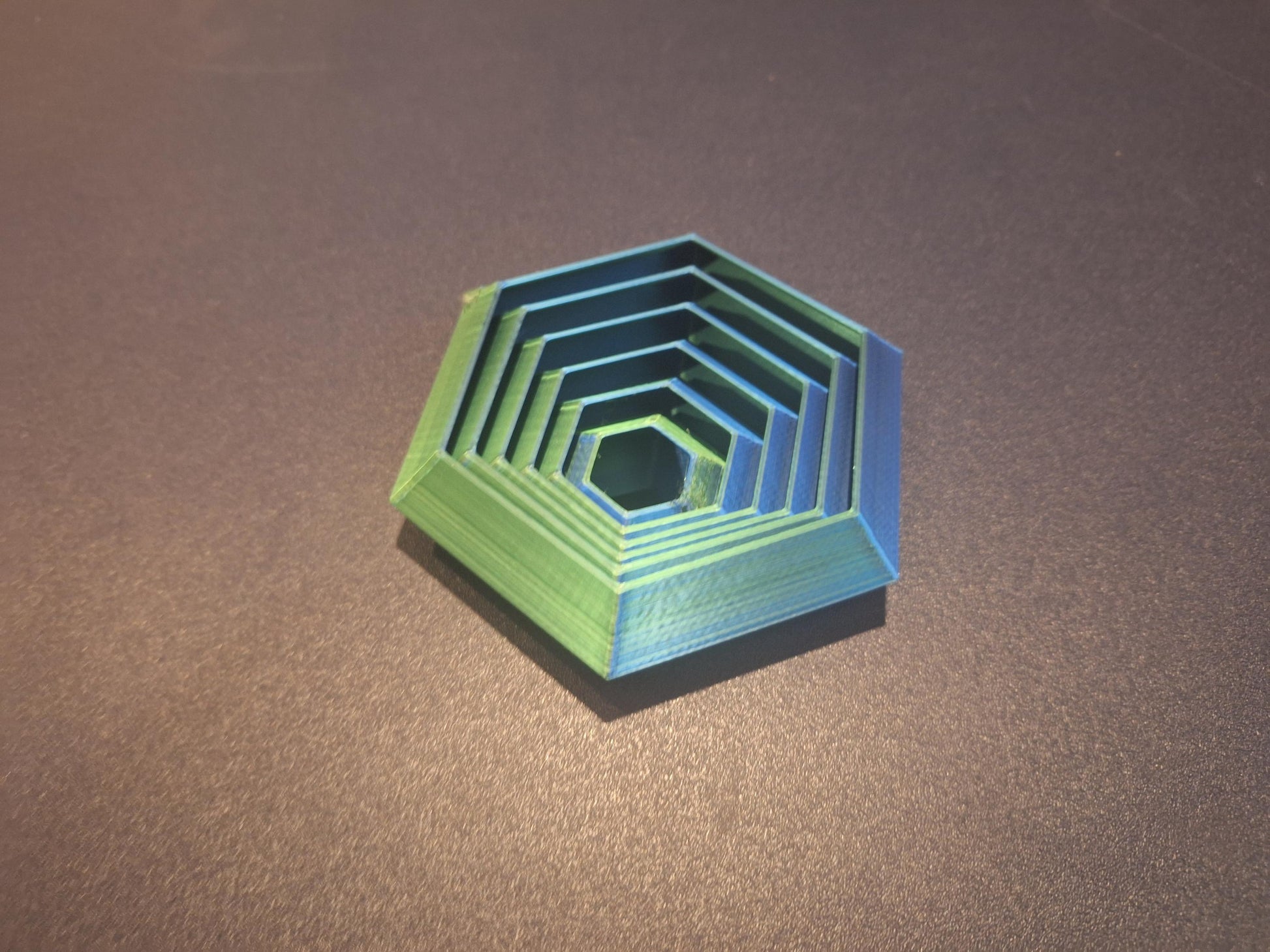 Hexagonal green and blue 3D printed board game organizer insert by KreativLayers on dark surface