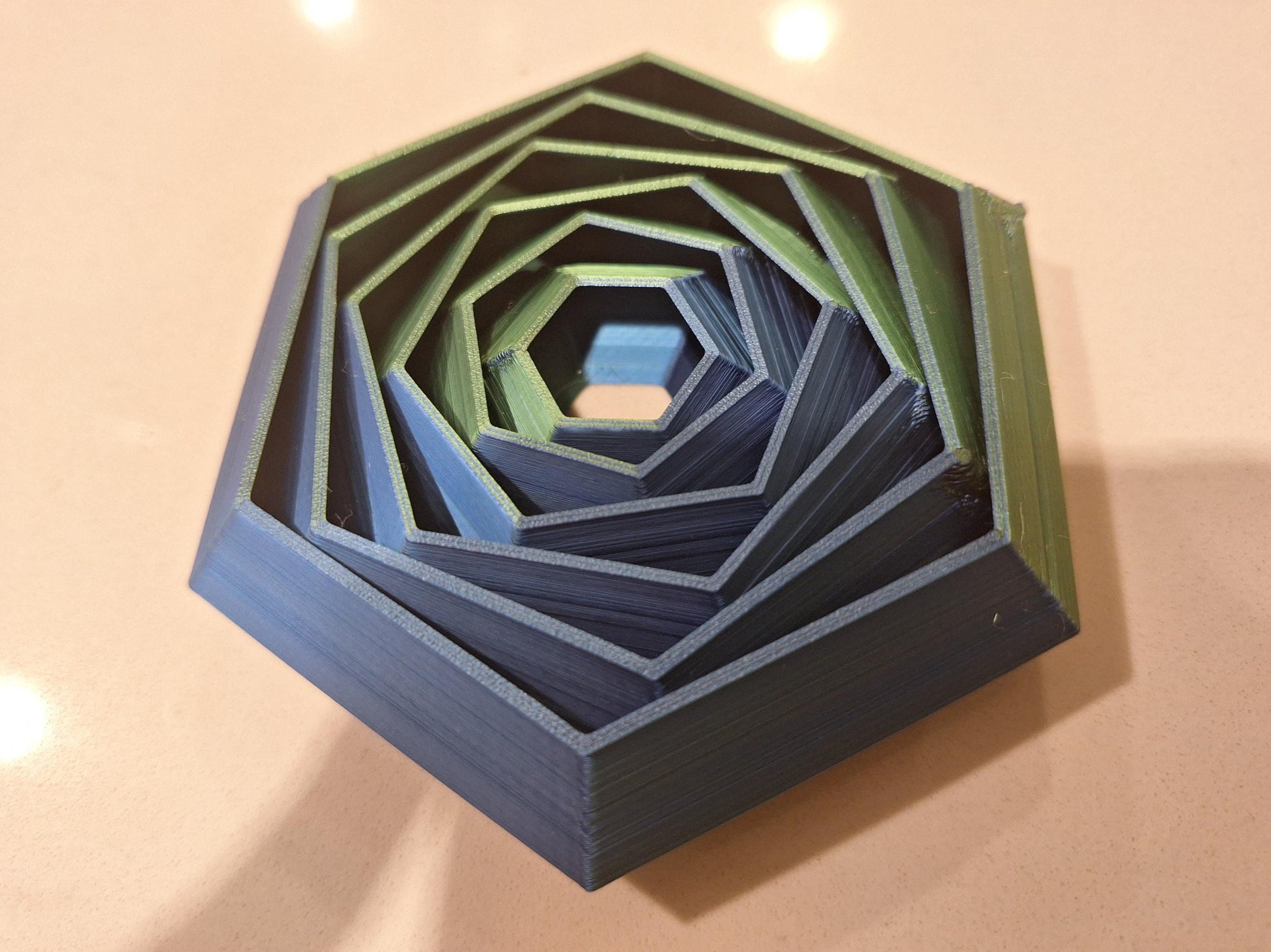 Stacked hexagonal 3D printed board game organizer in blue and green on tabletop