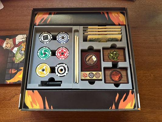 Board game organizer with poker chips, currency, and food-themed tokens in custom 3D insert