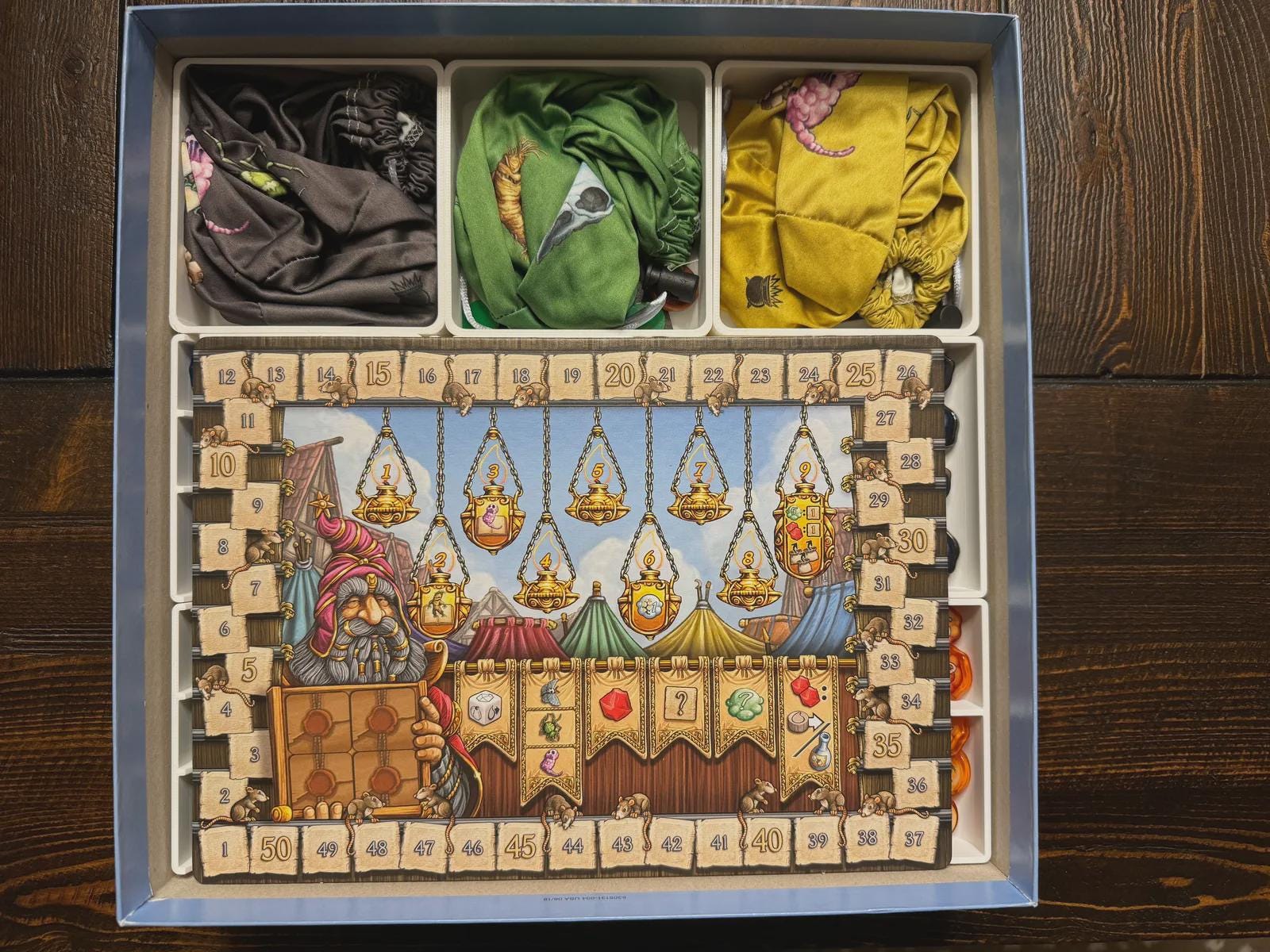 Board game organizer with colorful fabric bags and illustrated game board, KreativLayers storage