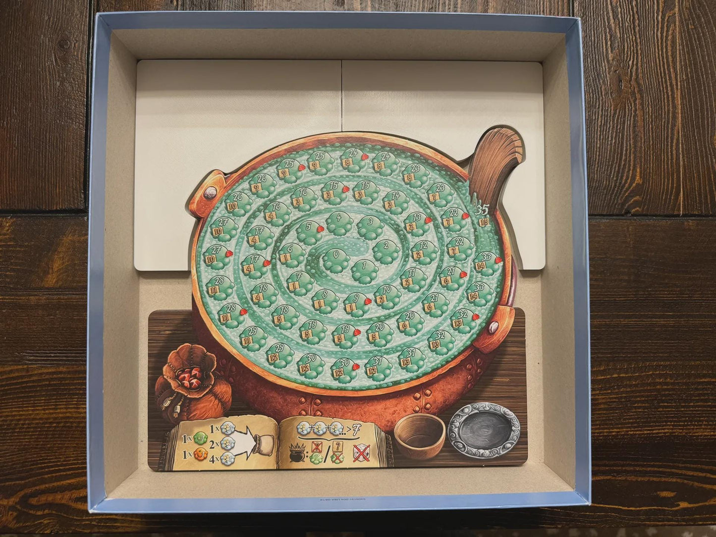 Board game organizer insert with a spiral cauldron board piece inside a game box, perfect for tabletop storage by KreativLayers.