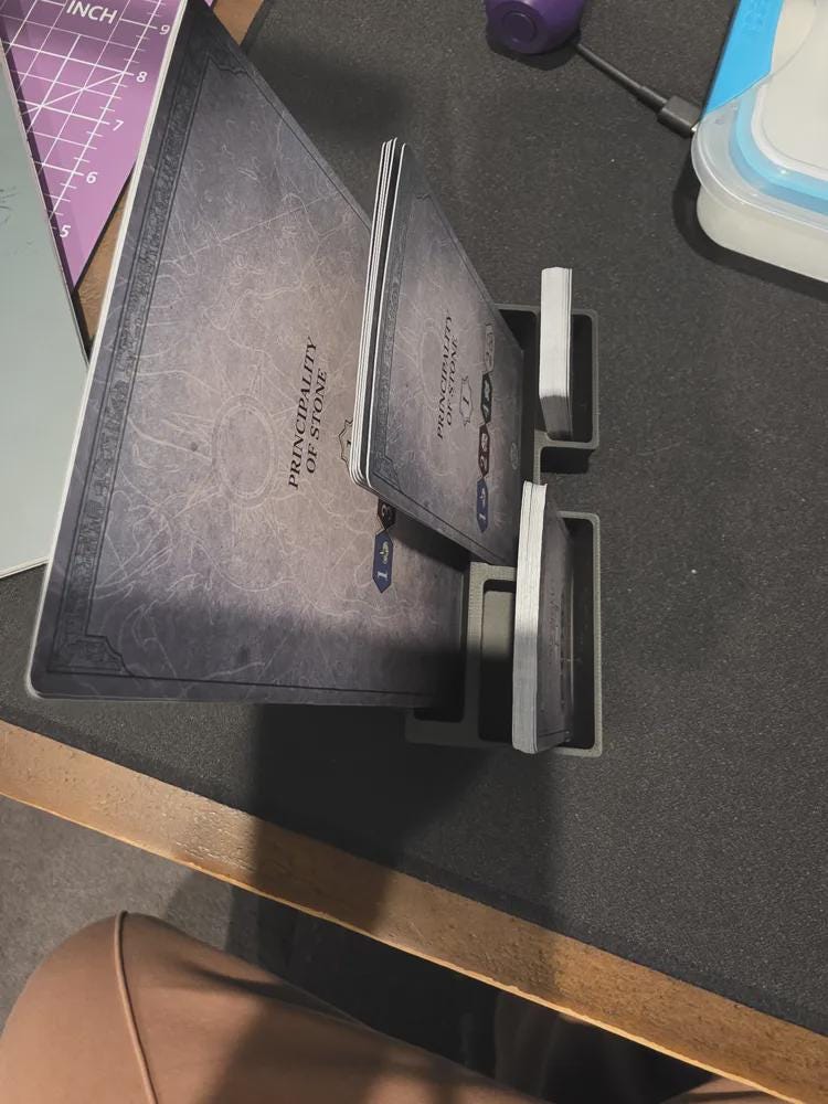 3D printed board game card organizer holding cards labeled Principality of Stone on table