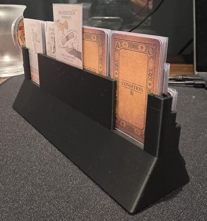 Black plastic card holder with board game cards on a tabletop, gaming accessory organizer