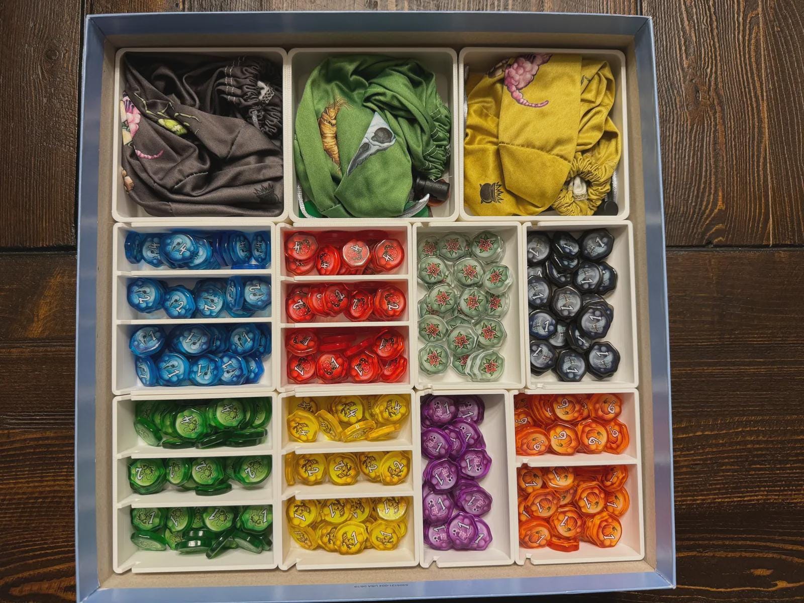 Board game organizer with 3D printed inserts holding colorful tokens and fabric bags, KreativLayers