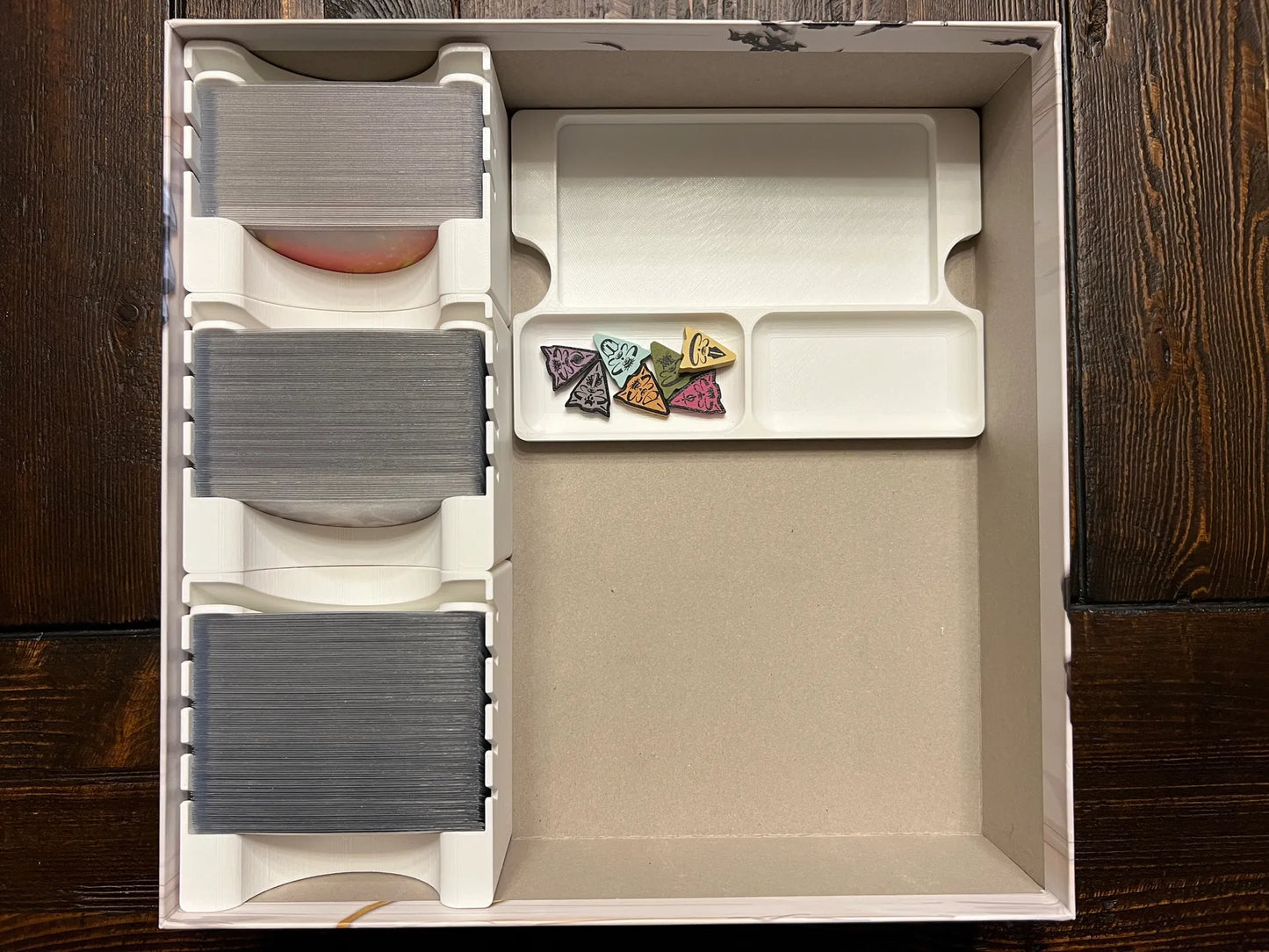 3D printed board game organizer with card and token trays inside game box on wooden table