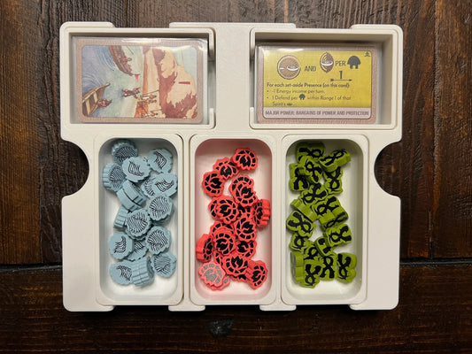 3D printed board game organizer holding game cards and colored tokens on a wooden table