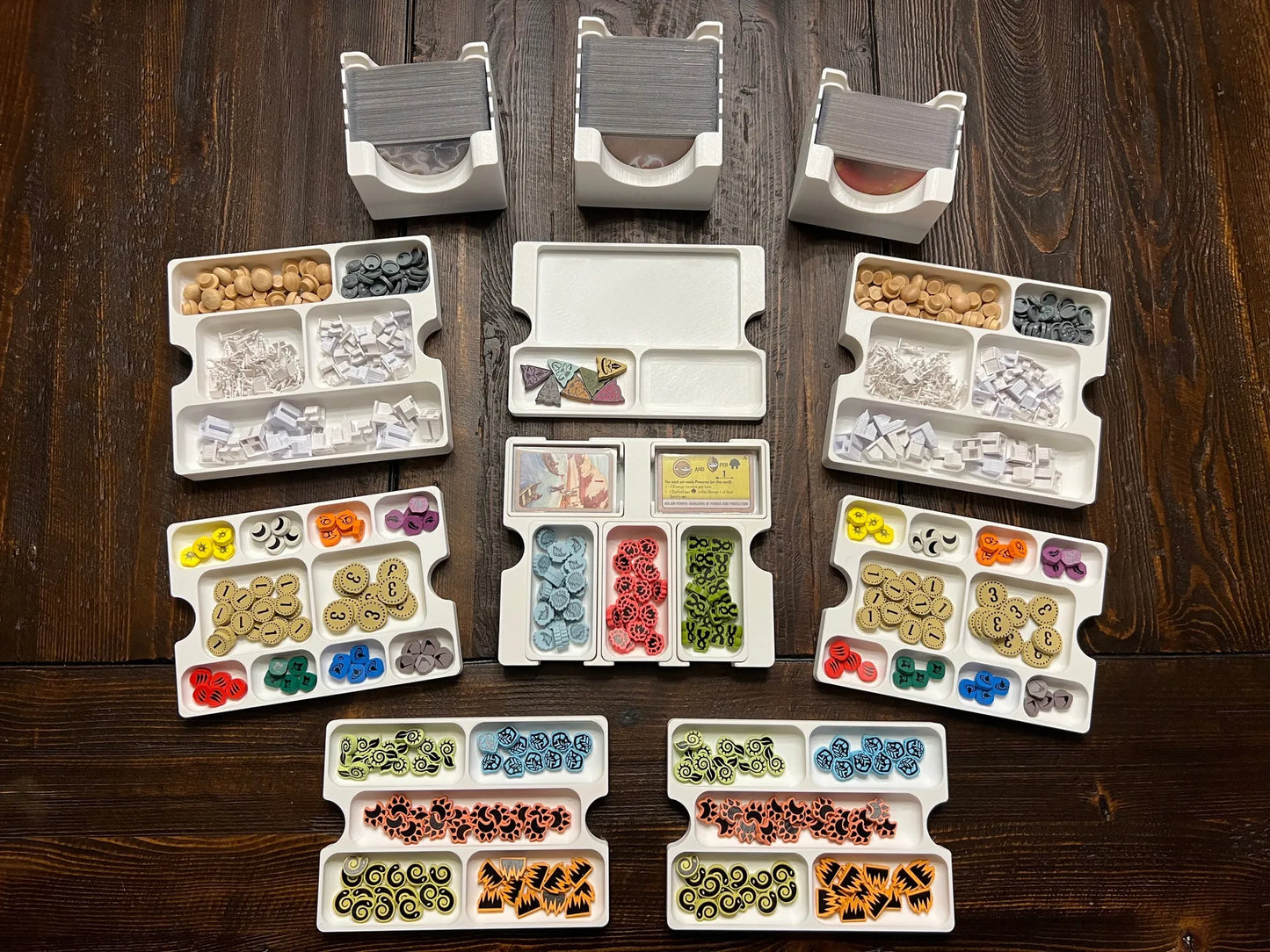 3D printed board game organizer with trays holding colorful tokens and cards on a wooden table