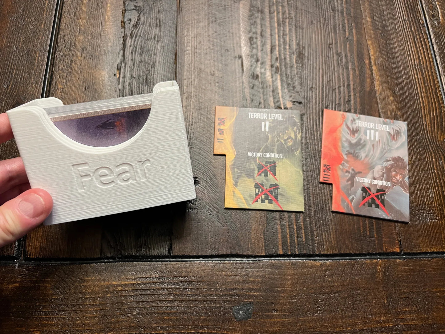 3D printed board game card holder labeled 'Fear' with game cards on wooden table, KreativLayers organizer