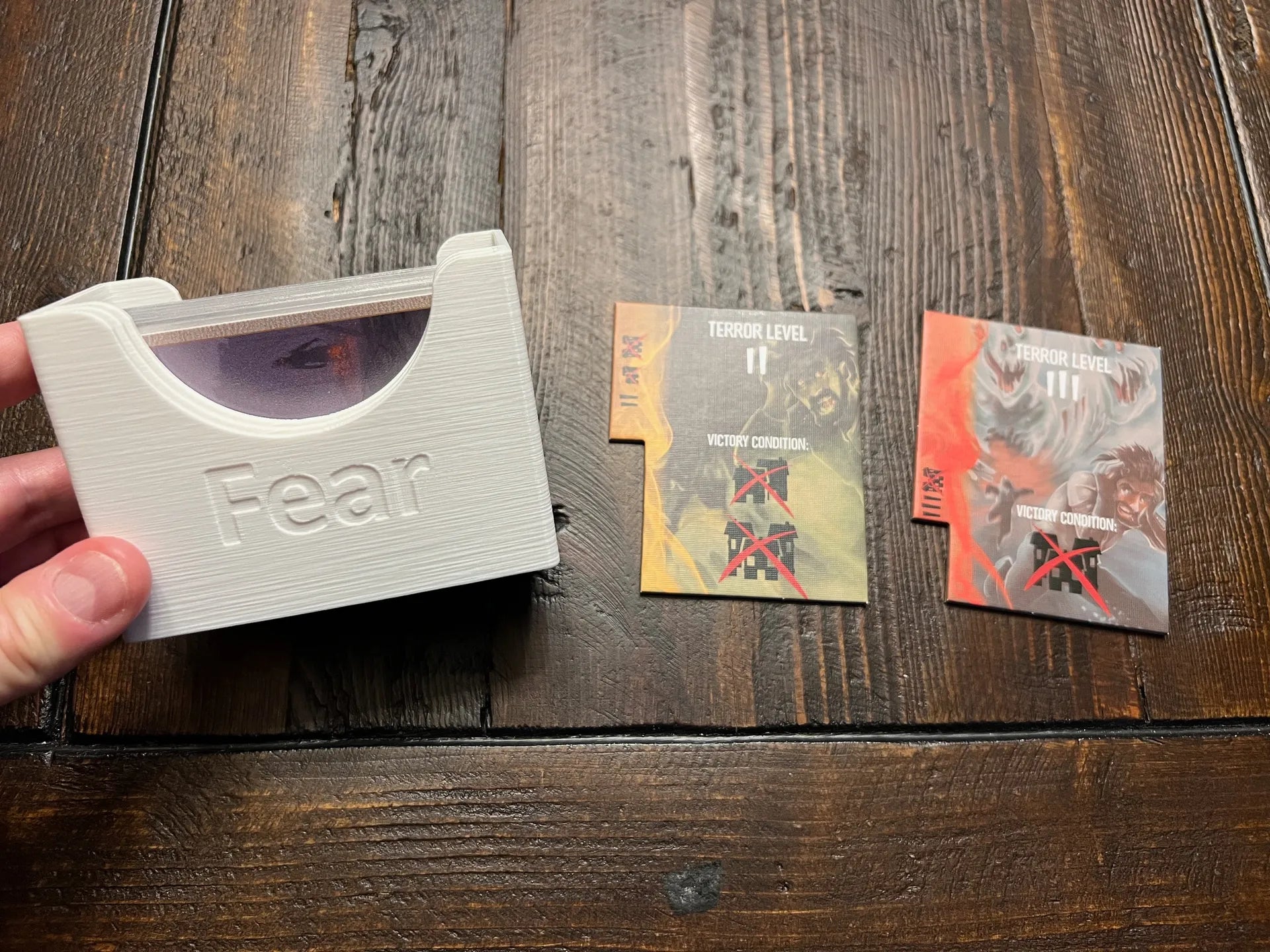 3D printed board game card holder labeled 'Fear' with game cards on wooden table, KreativLayers organizer