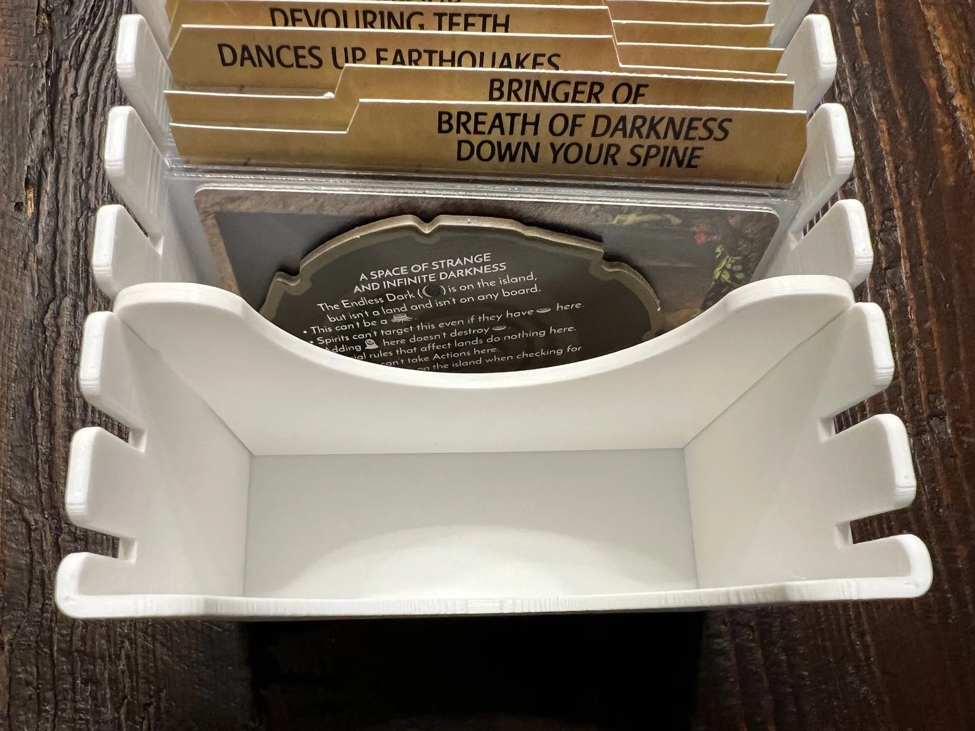 3D printed board game organizer tray holding labeled tabletop game cards on wood surface