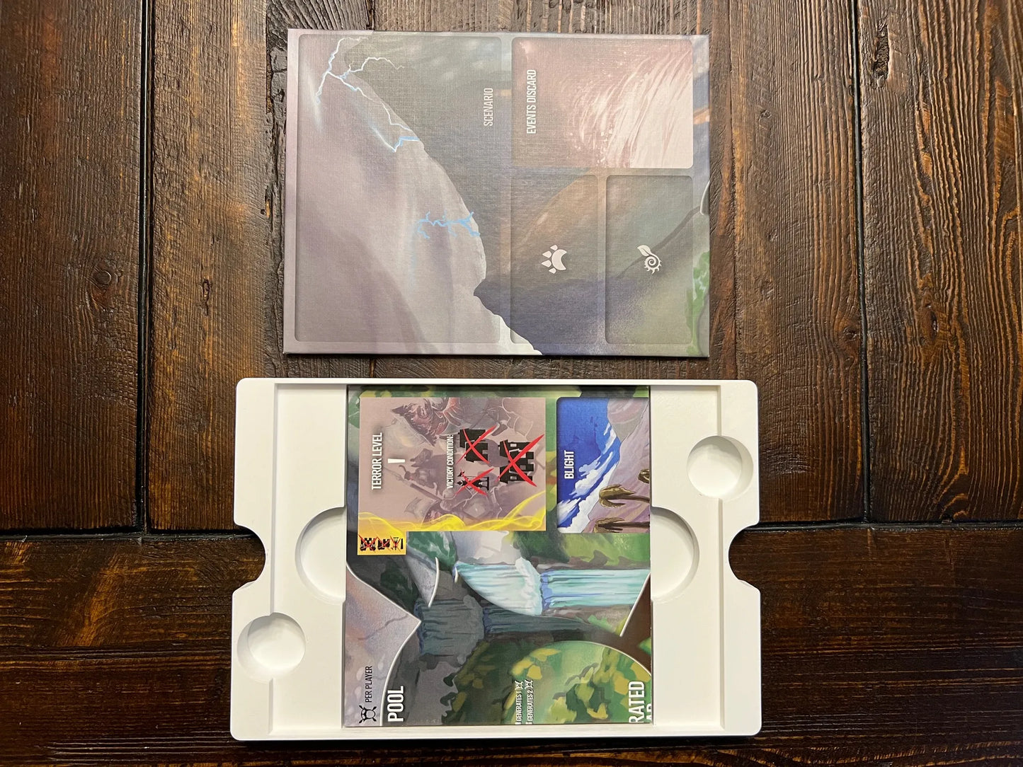 Board game organizer tray with custom inserts and game cards on a wooden table