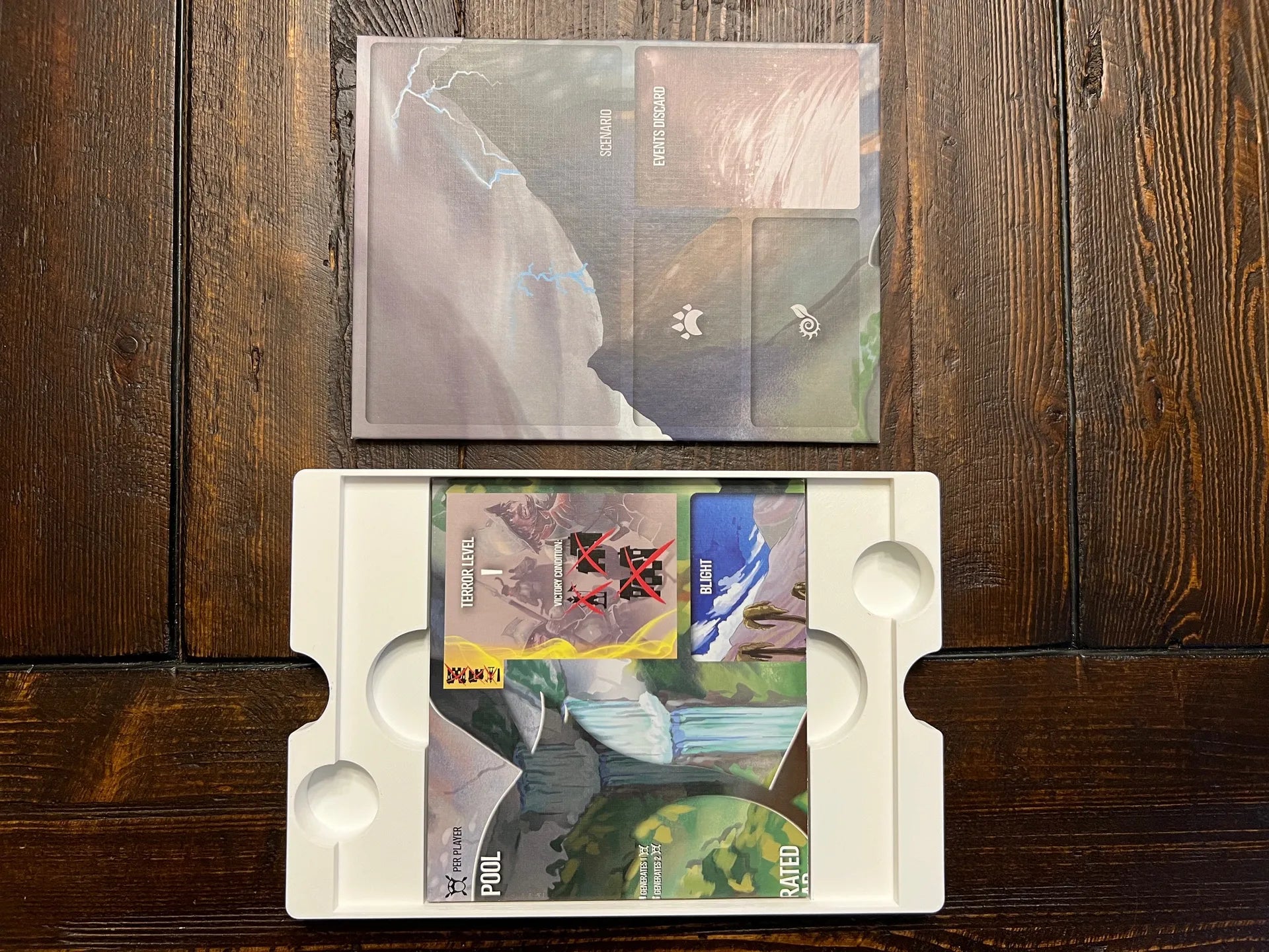 Board game organizer tray with custom inserts and game cards on a wooden table